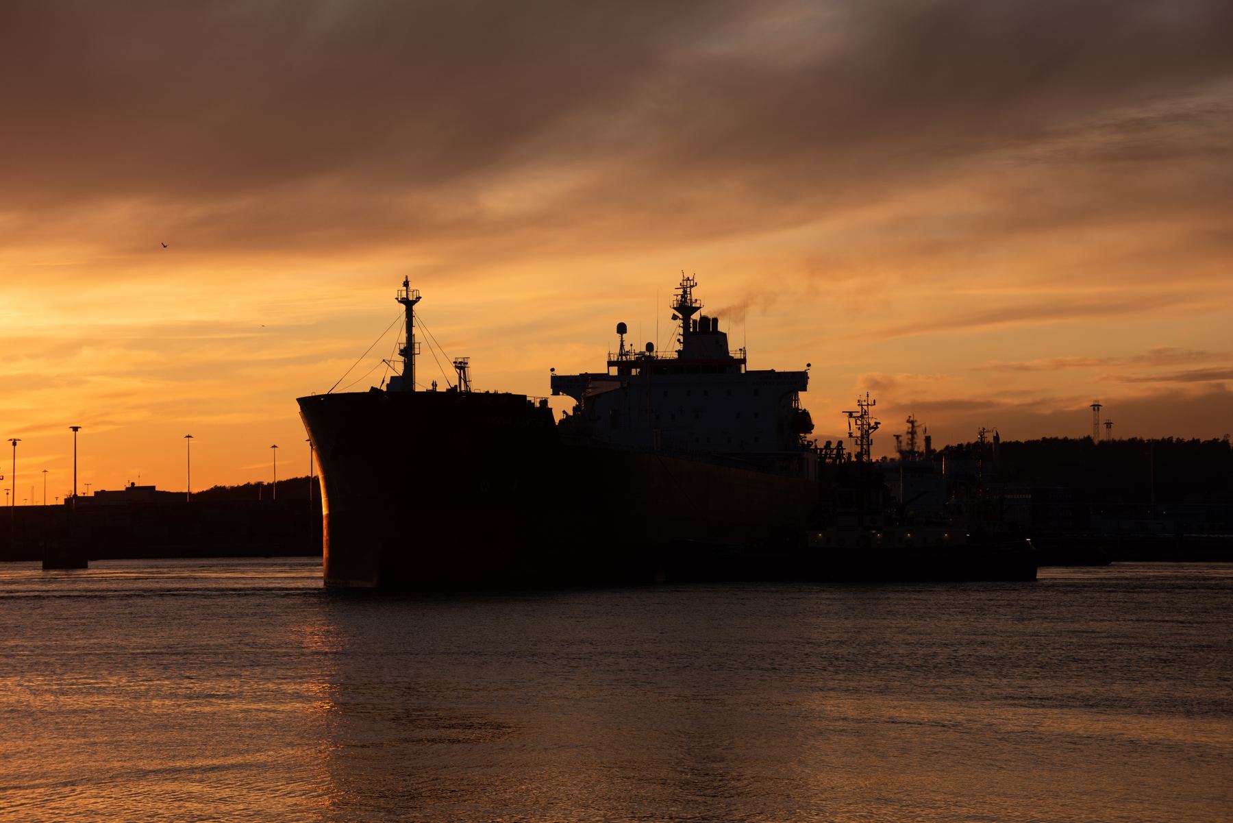 Tanker silhouetted against a sunset in port